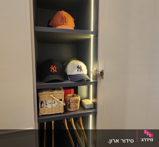 כובעים ומעילים מסודרים בארון מואר עם מדפים